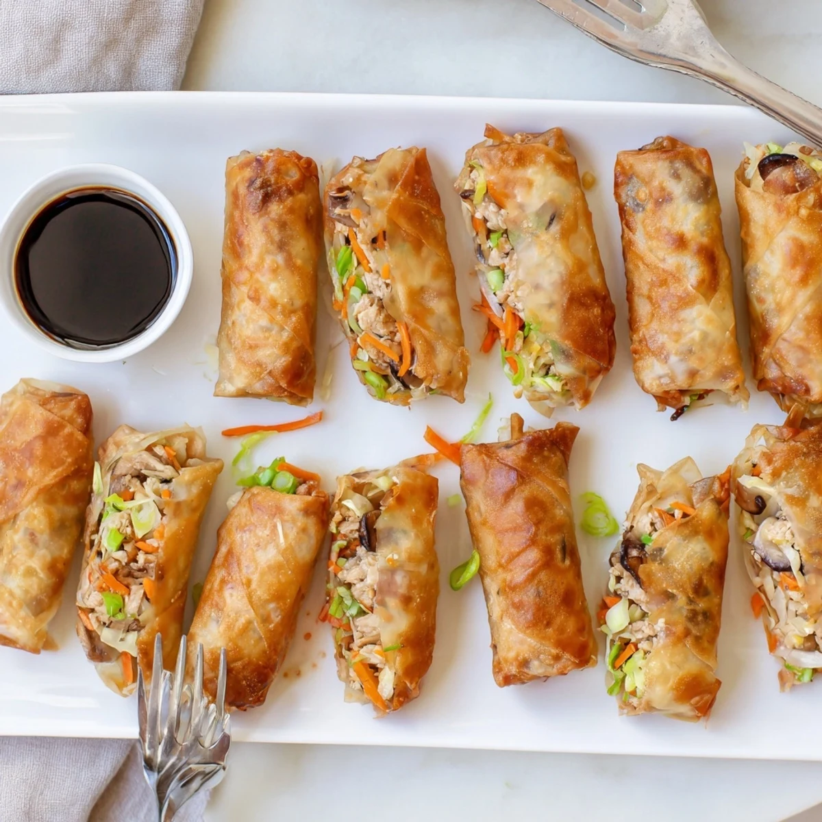 Golden crispy rice paper spring rolls filled with savory vegetables and protein on a serving plate