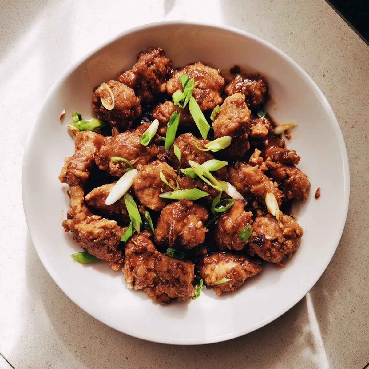 Bite-sized Mongolian chicken simmered in savory caramelized sauce with fresh green onion garnish