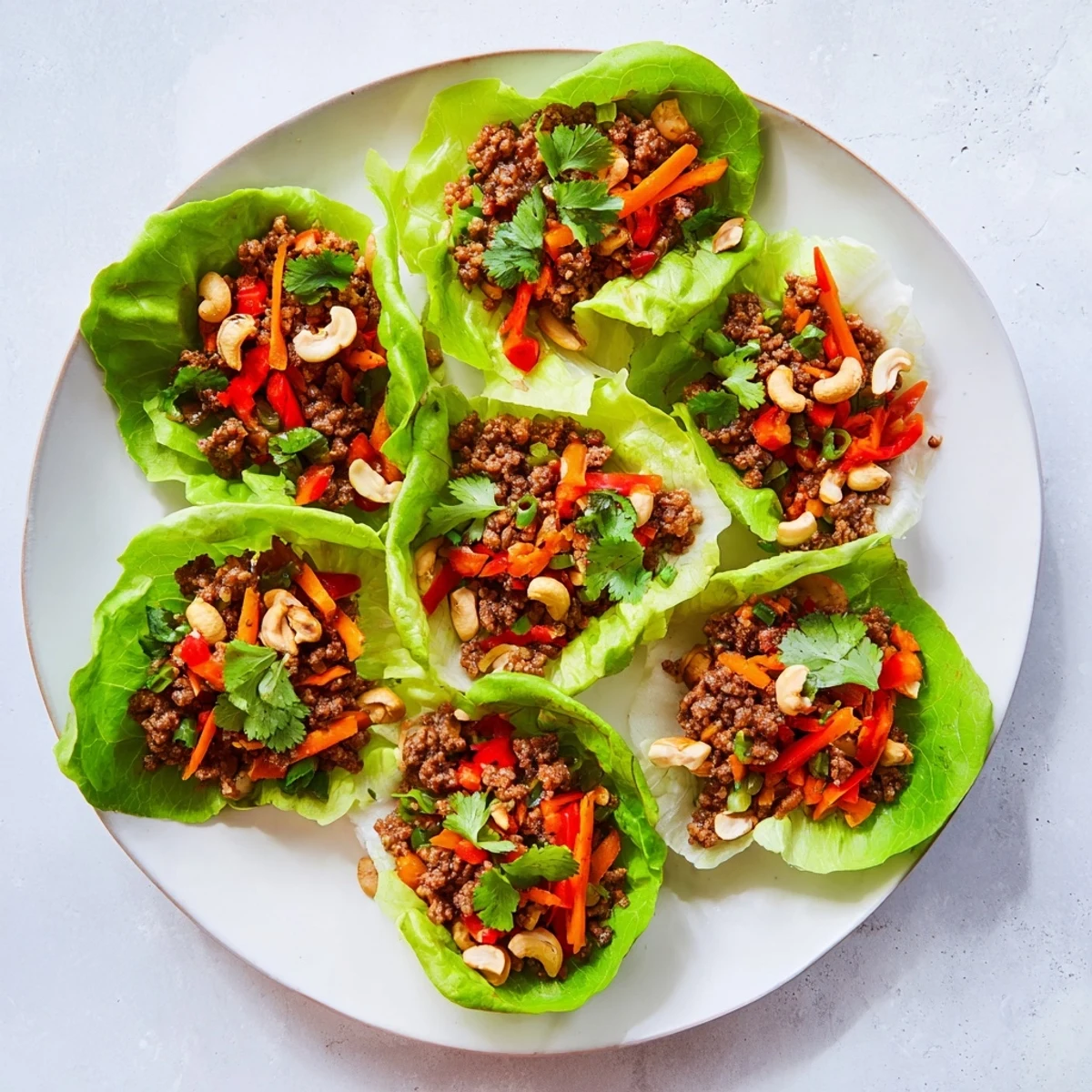 Fresh beef and cashew lettuce cups topped with vibrant cilantro and diced vegetables