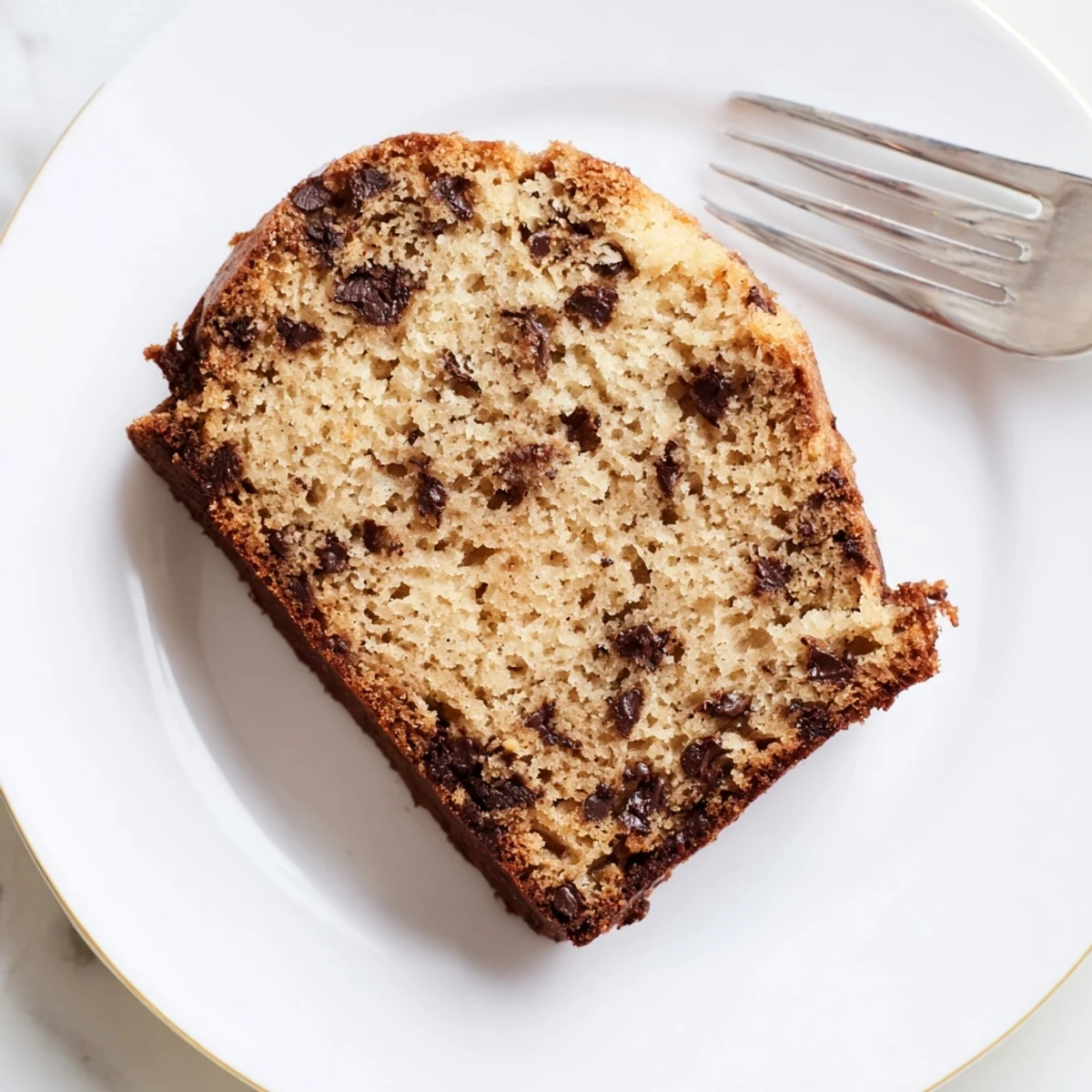 Golden chocolate chip banana bread loaf with melted chips on top, freshly baked and ready to slice