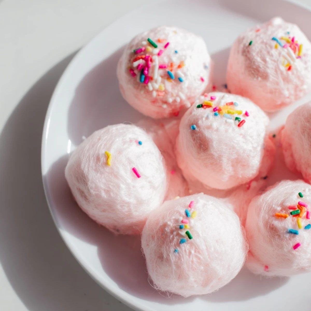 Mini cotton candy cheesecake puff balls with fluffy pastel coating on decorative serving plate