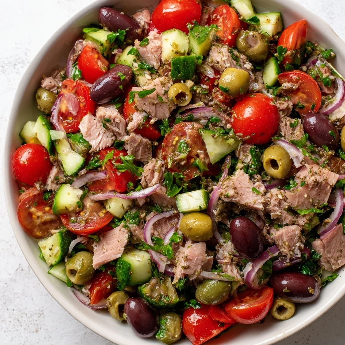 Colorful Mediterranean tuna salad loaded with ripe tomatoes, olives, and crisp fresh cucumbers