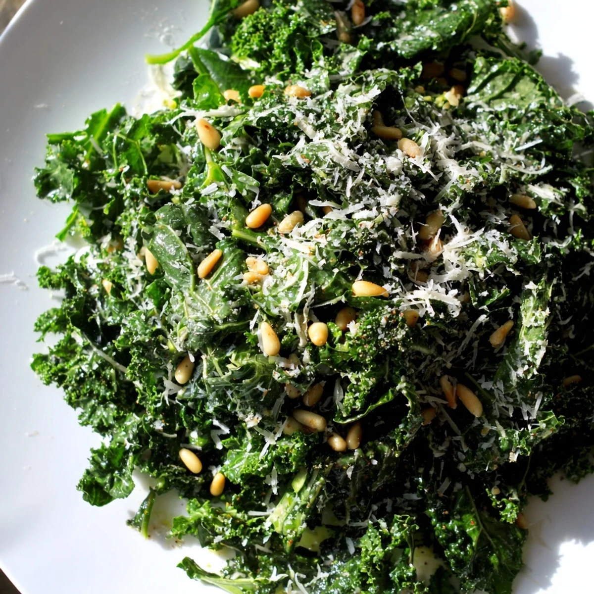 Tender massaged kale leaves glistening with zesty garlic lemon Parmesan dressing in a wooden bowl