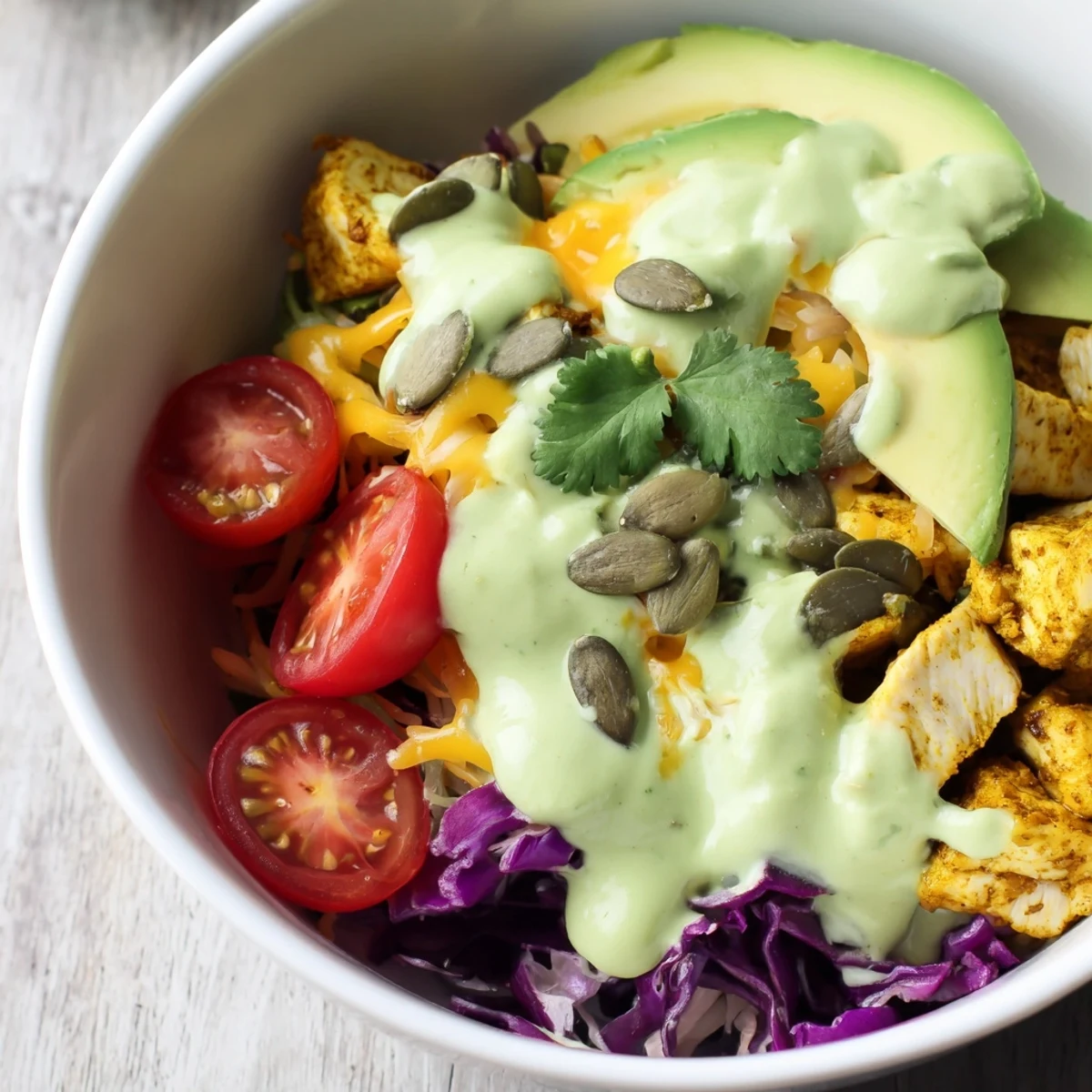 Colorful keto bowls with seasoned chicken, crisp vegetables, and creamy avocado dressing ready to serve