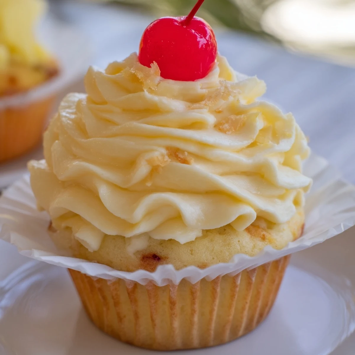 Golden Dole Whip Cupcakes topped with creamy pineapple whipped frosting and cherry garnish