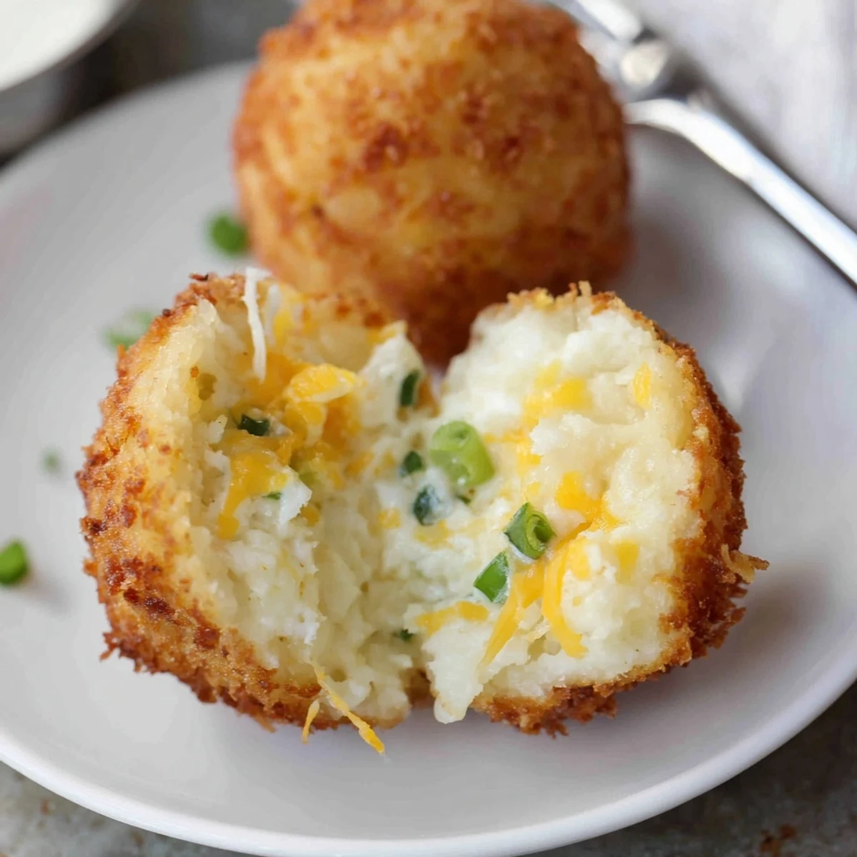 Crispy Fried Mashed Potato Balls showing cheesy interior and scallion garnish