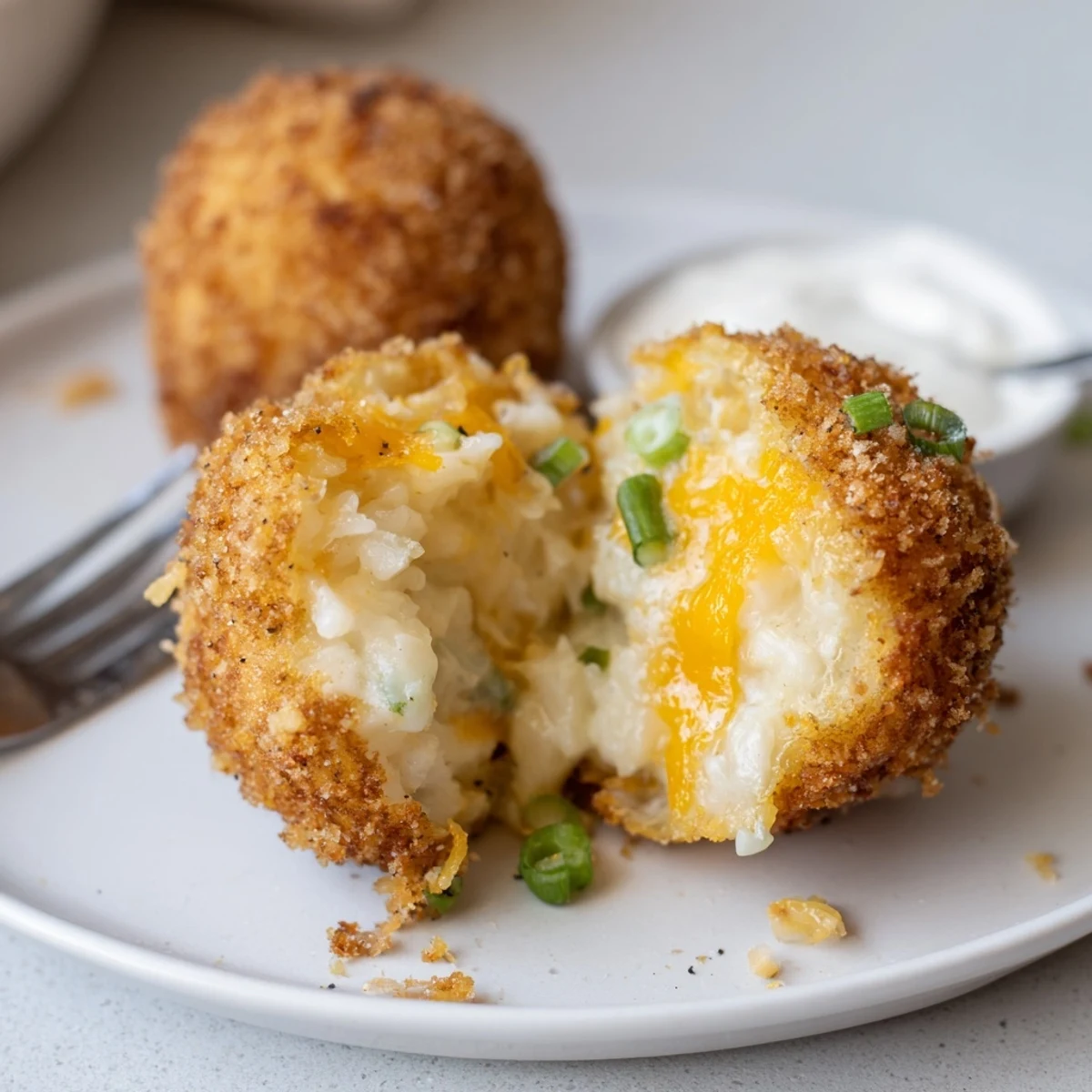 Handheld Fried Mashed Potato Balls steaming hot, served with spicy ketchup