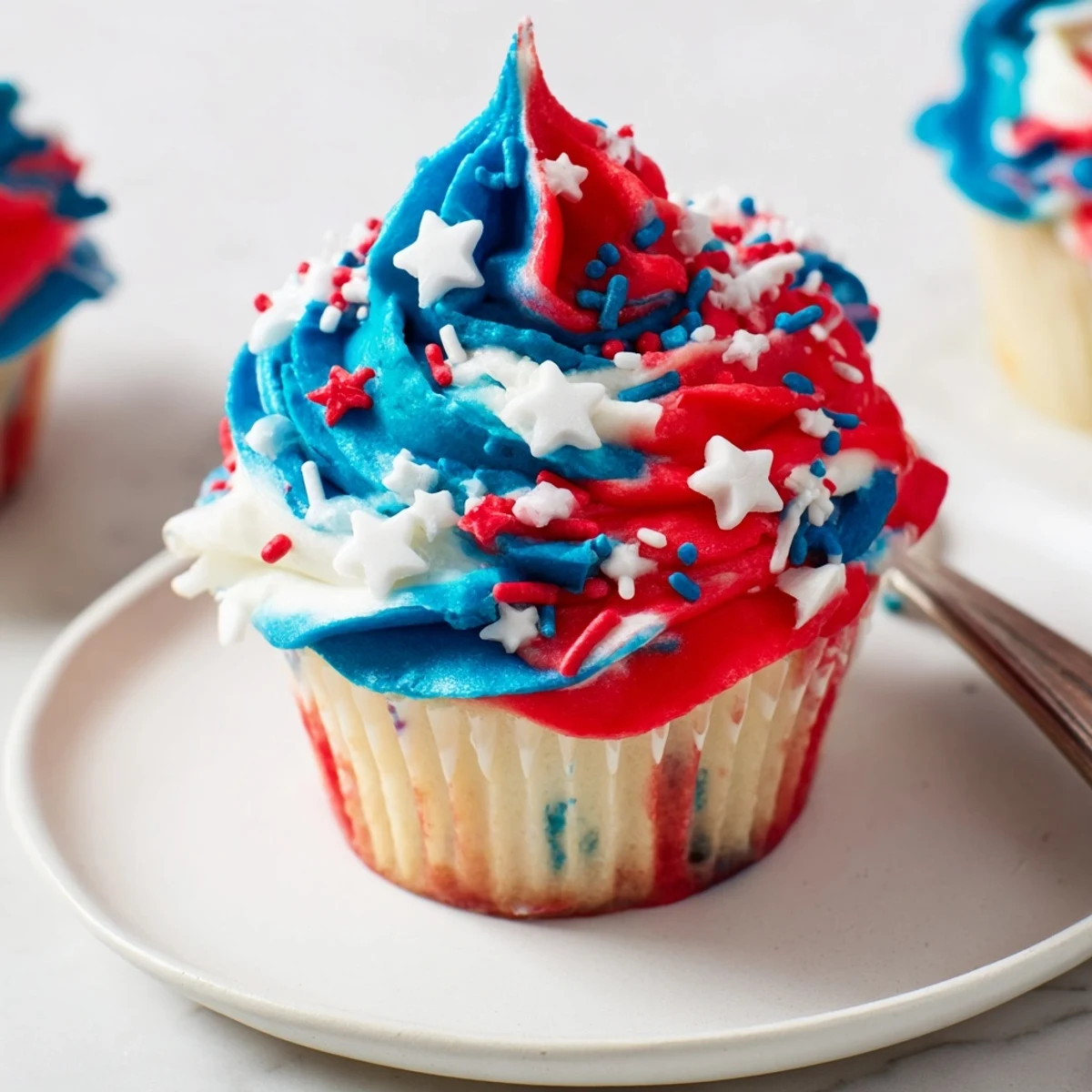 Plated Patriotic Firework Cupcakes topped with crunchy sprinkles, perfect for backyard barbecues