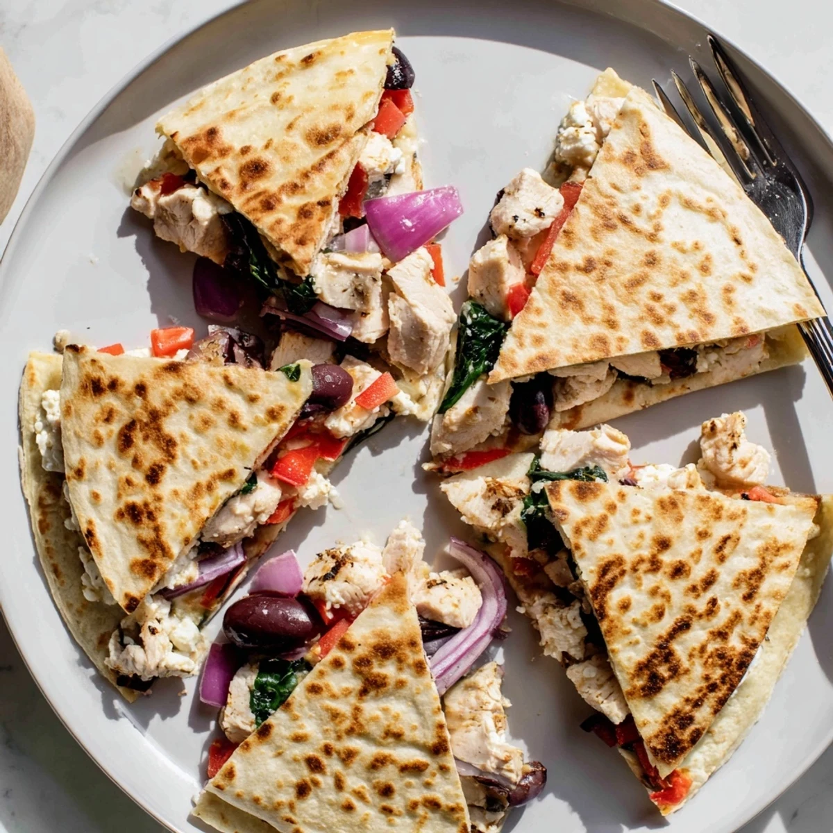 Golden Greek chicken quesadillas with melted mozzarella and feta on a wooden serving board