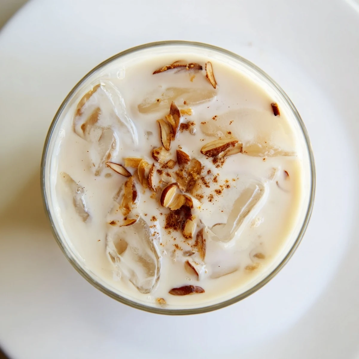 Golden roasted almond milk drink with cream garnished with almond slivers on ice