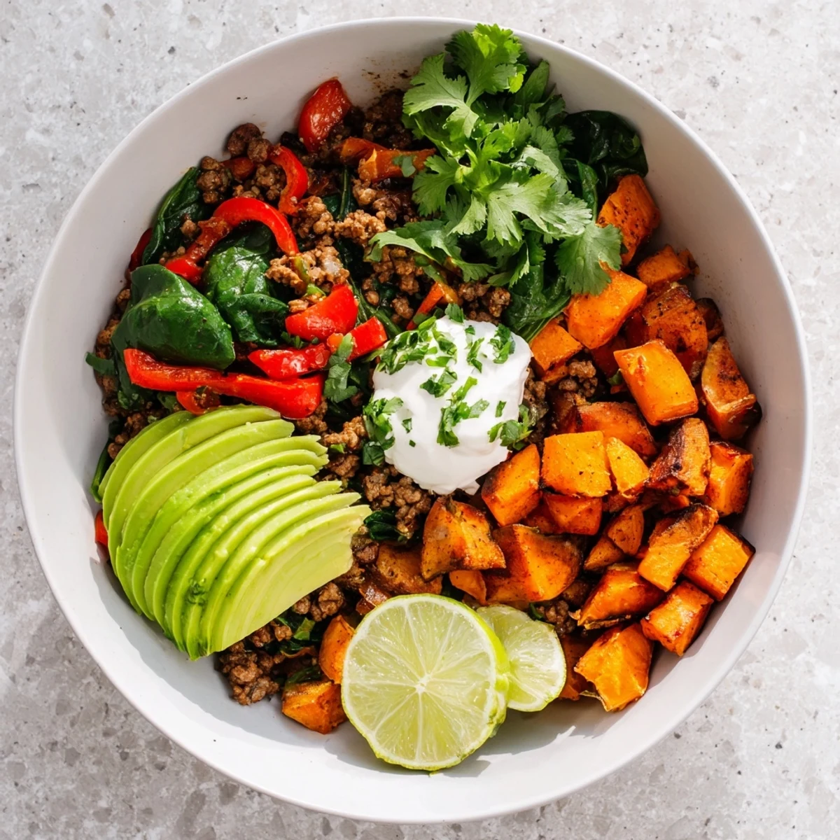 Golden roasted sweet potatoes topped with seasoned ground beef and fresh avocado in a beef sweet potato bowl recipe