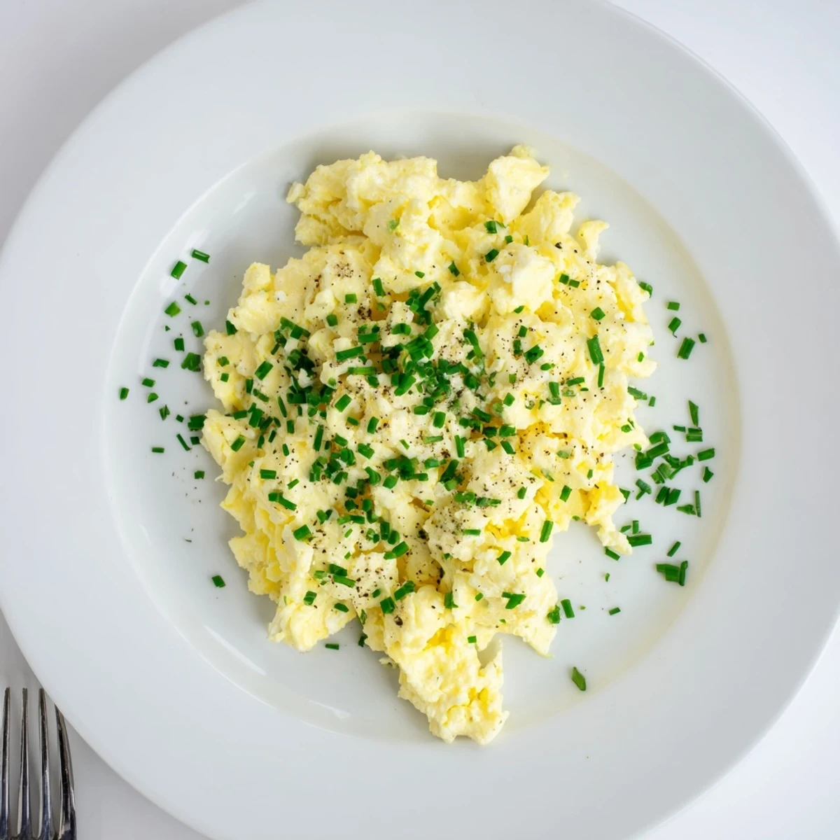 Warm skillet of Cottage Cheese Scrambled Eggs with Chives, bright green garnish