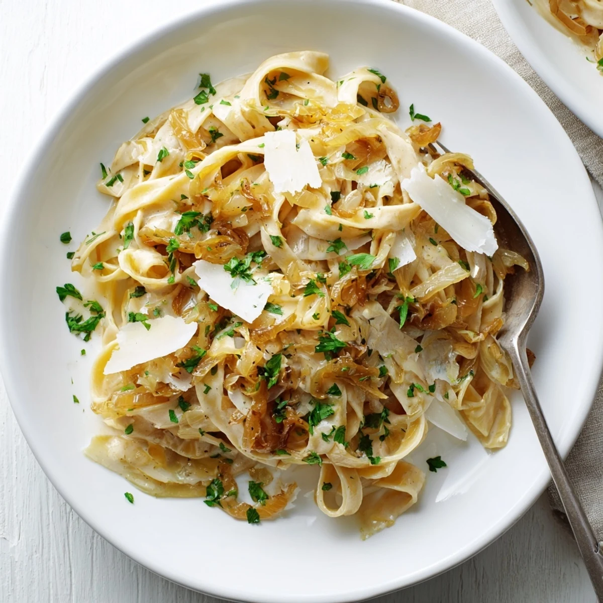Bowl of caramelized onion cream pasta featuring sweet onions and grated Parmesan in rich cream sauce