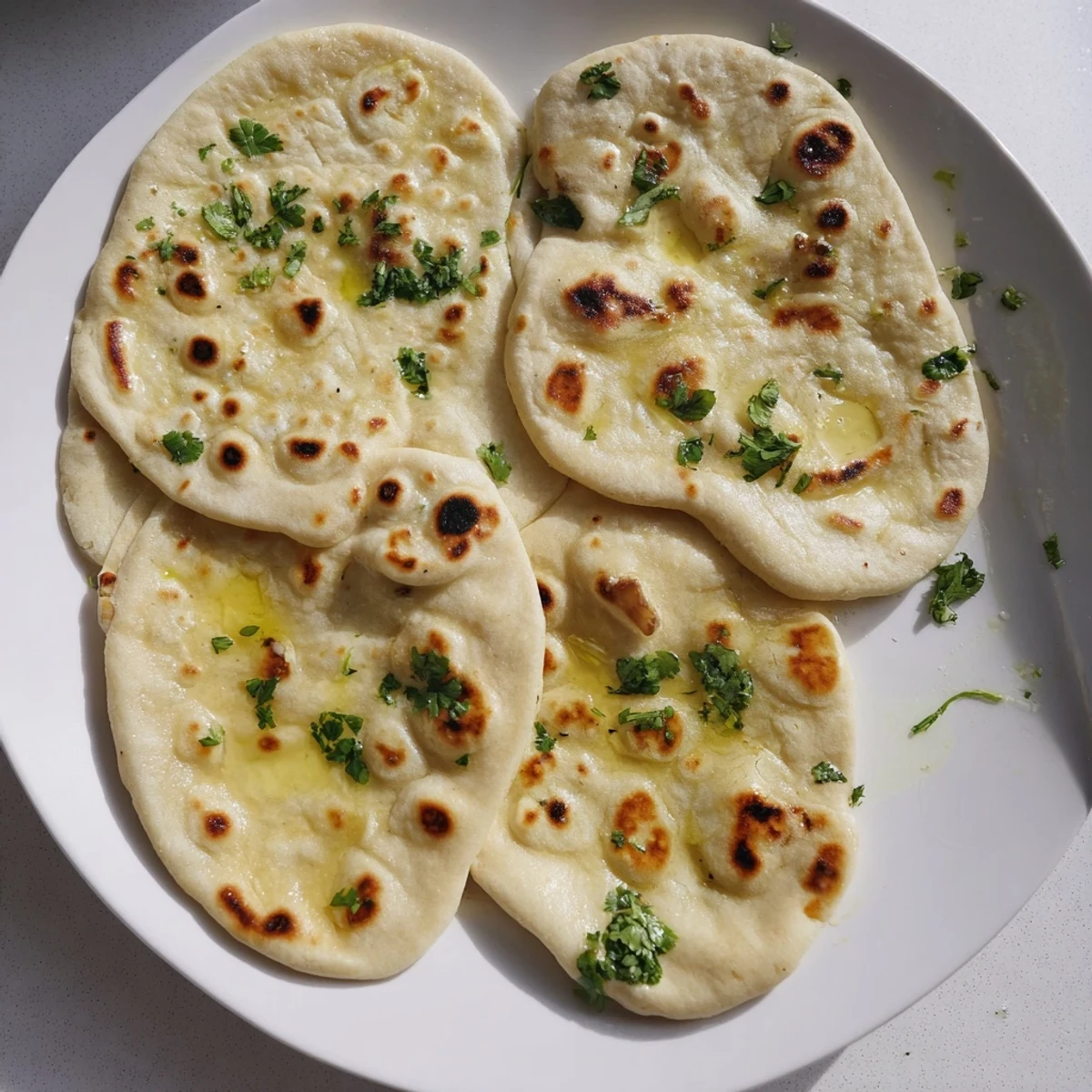 Warm homemade naan bread featuring bubbly charred spots and glossy butter coating