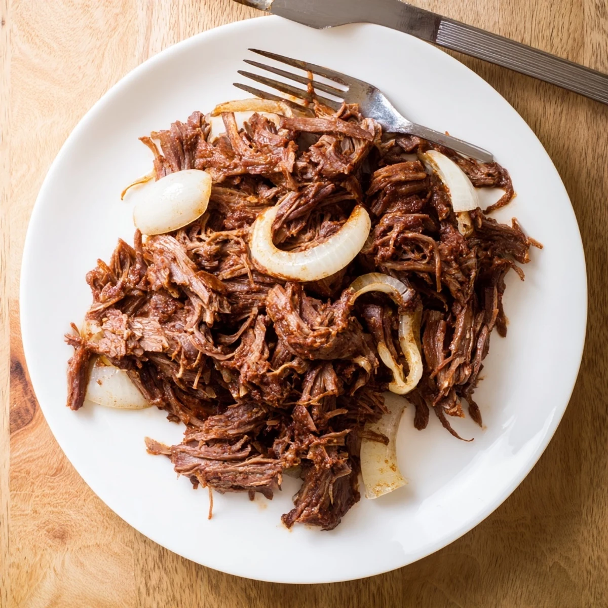 Rich and juicy slow cooker beef barbacoa served in a bowl over steaming Mexican rice with pickled red onions