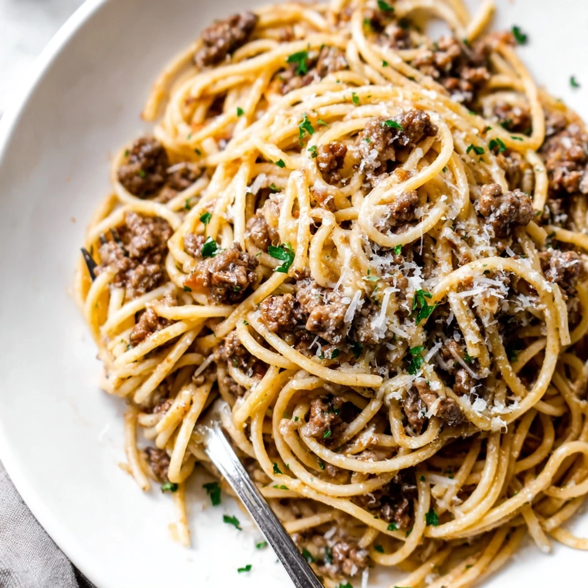 Garlic butter pasta with ground beef topped with melted Parmesan and fresh parsley