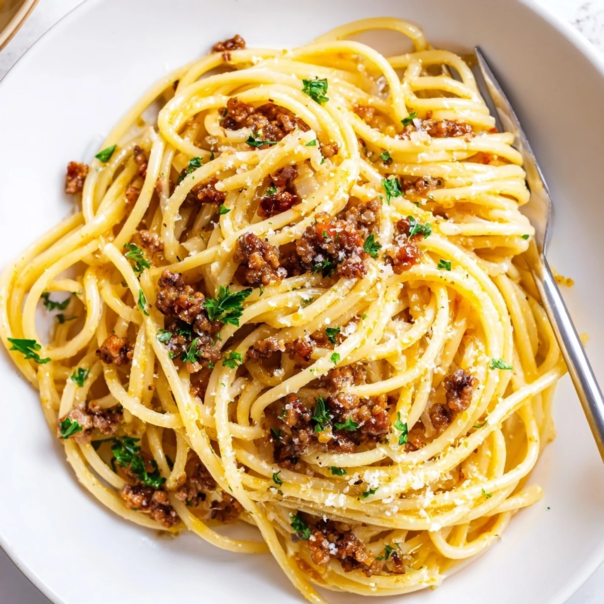 Steaming plate of garlic butter pasta with ground beef coated in silky sauce