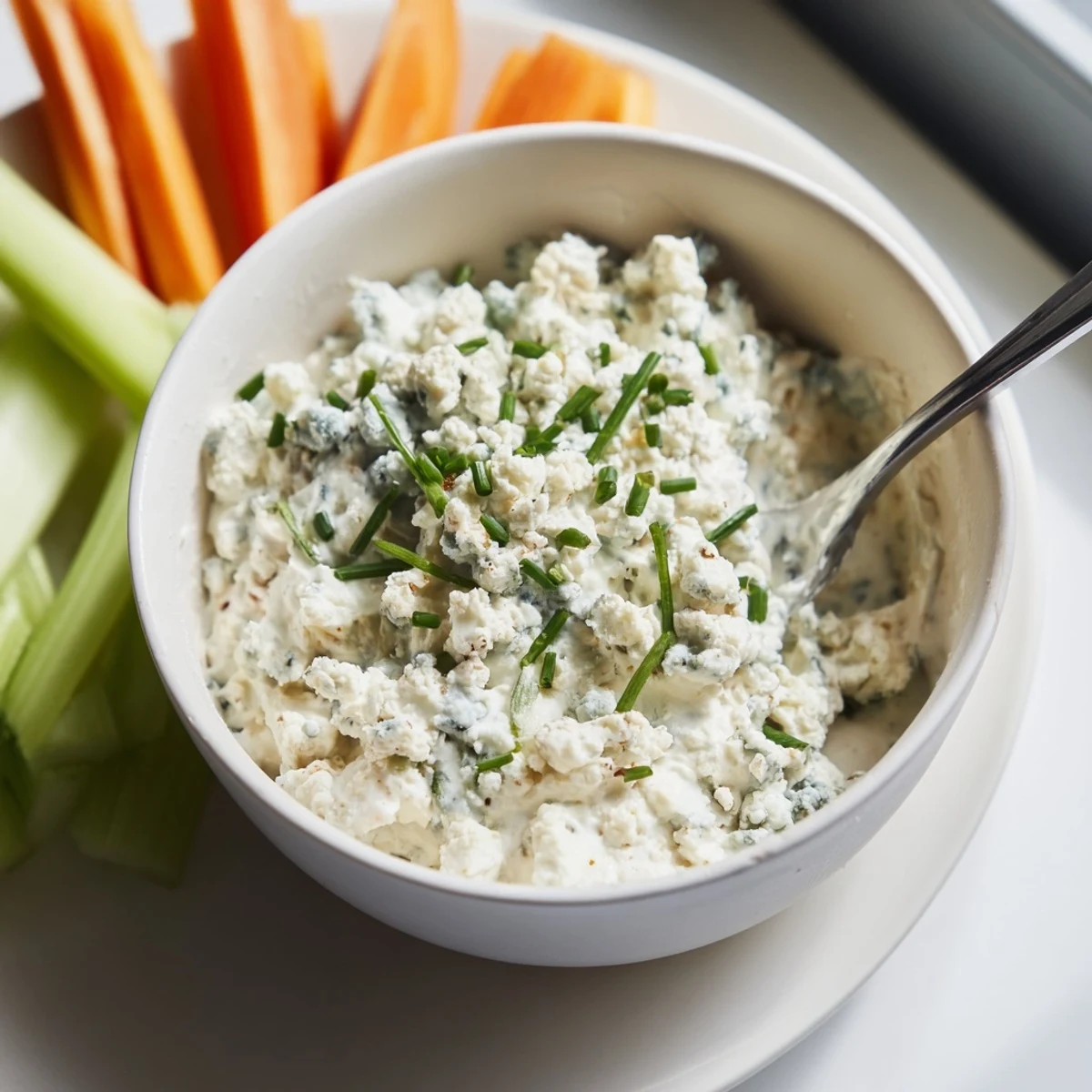 Thick blue cheese dip topped with crumbles and chives served alongside crispy chips