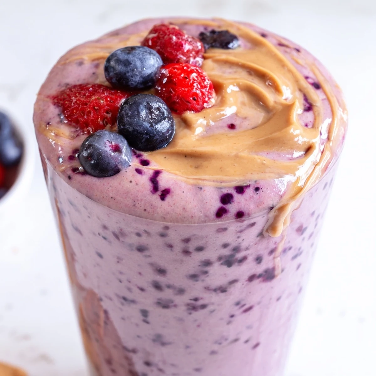 Creamy peanut butter berry smoothie swirled with vibrant berries served in a tall mason jar