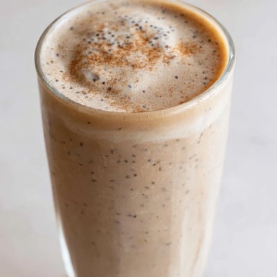 Thick frothy banana protein coffee smoothie poured over ice for morning energy
